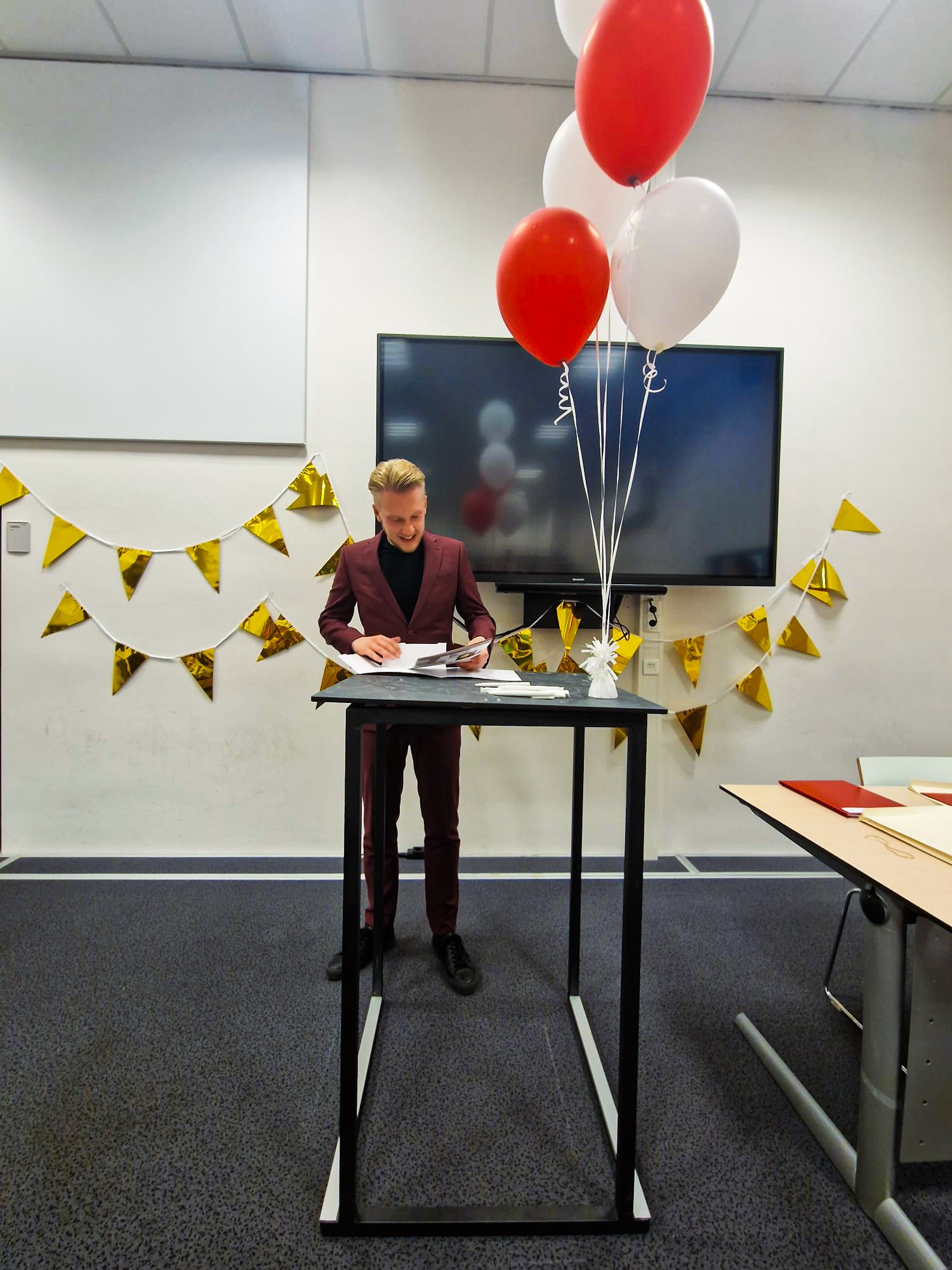Rick bekijkt zijn net overhandigde diploma aan een statafel.