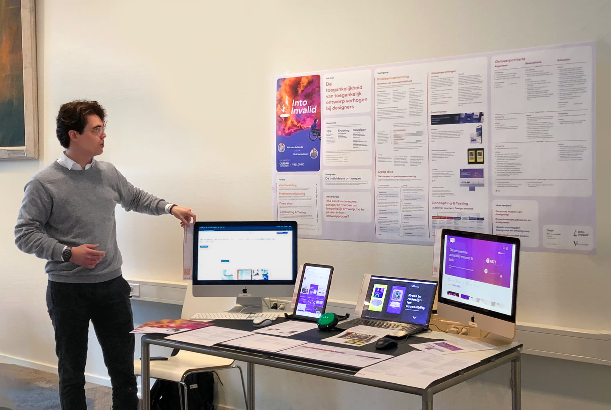 Een foto waarop Rick van de Sande zijn expositie presenteert aan docenten en medestudenten tijdens de tweede tafelpresentatie.