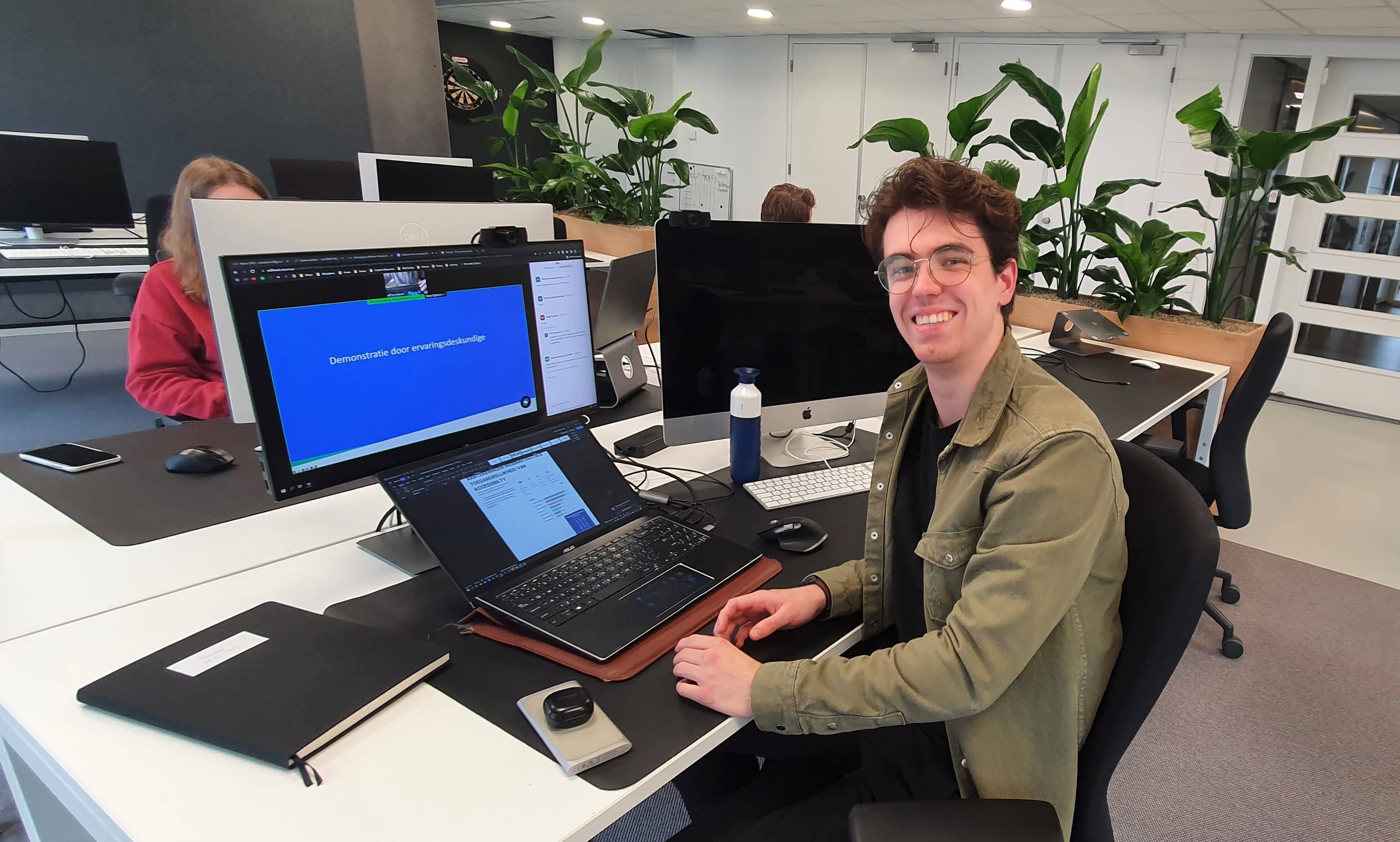 Rick van de Sande volgt op zijn computer een webinar van Stichting Accessibility en lacht naar de camera.